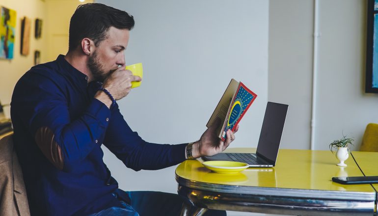 homem tomando café e lendo um livro